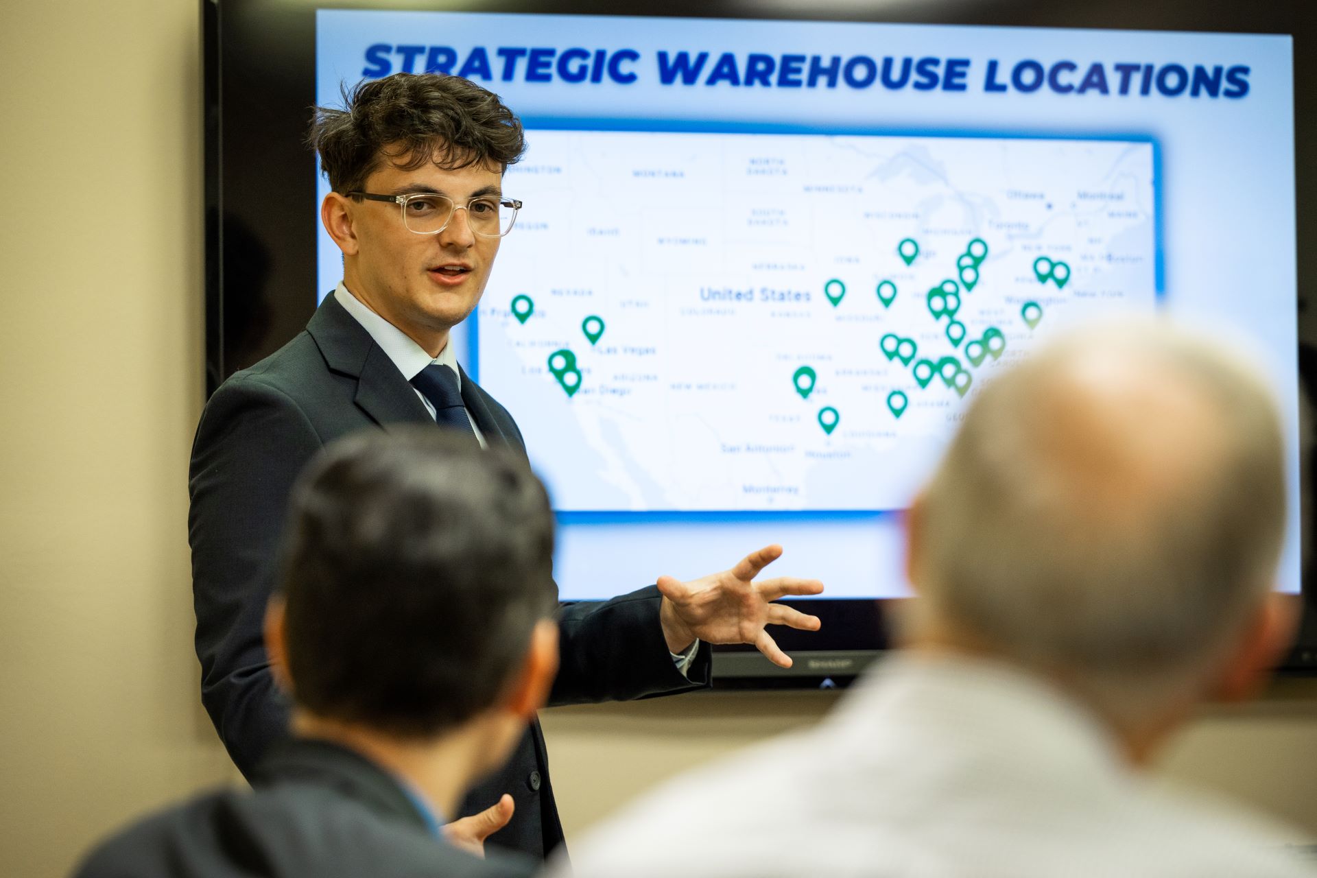 Professor in a suit giving a presentation on strategic warehouse locations